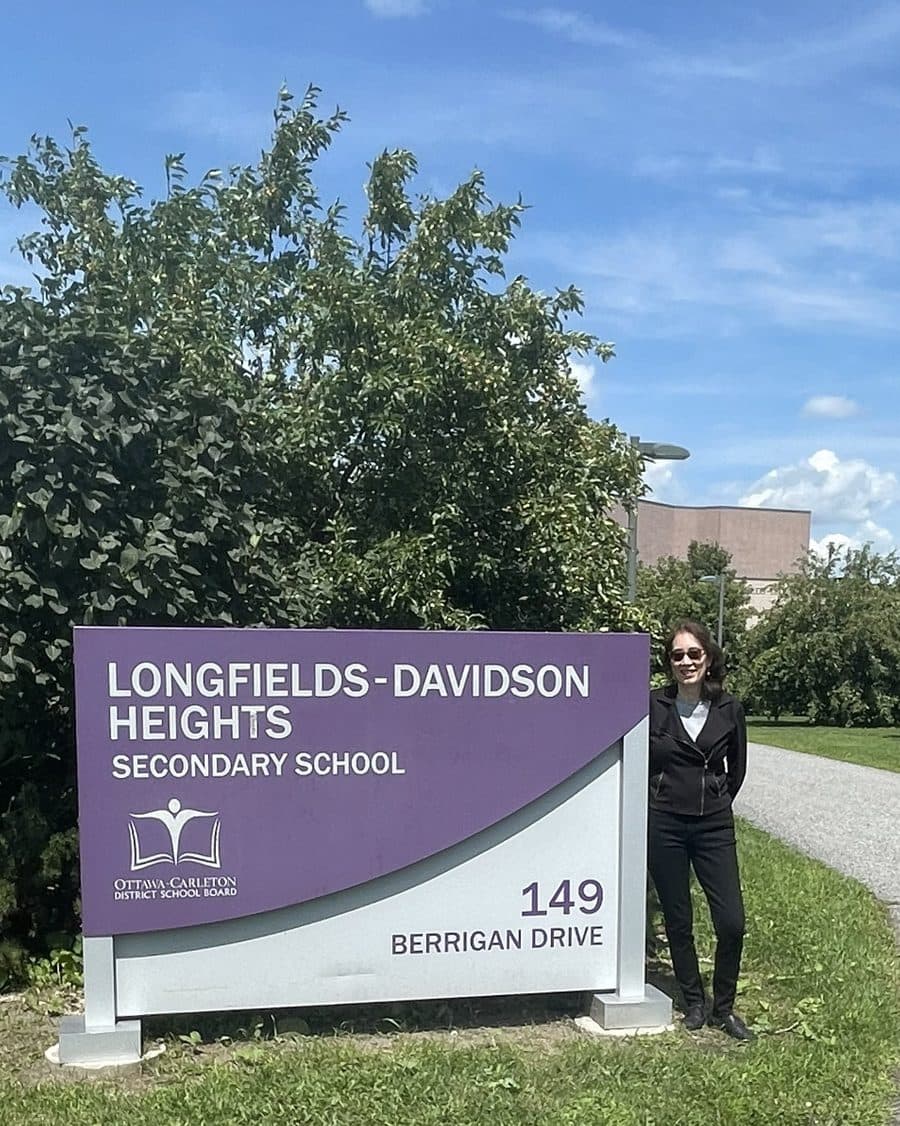 Brenda Abramson standing beside the Longfields-Davidson Heights Secondary School sign in Barrhaven